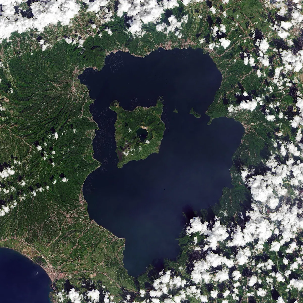 Satellite view of Lake Taal in the Philippines, with Volcano Island in the middle of the lake and a small crater lake at the island's center